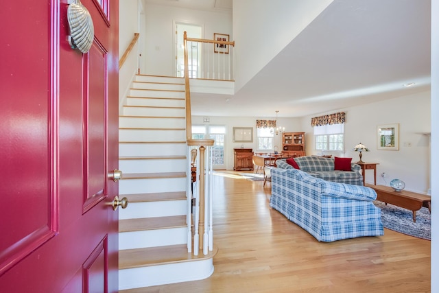 foyer entrance with light wood finished floors, stairway, and a notable chandelier