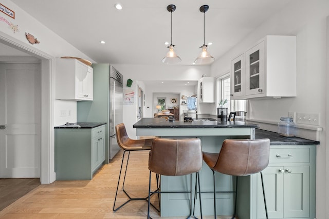 2 Seaview Rd, Orleans, MA 02653 - kitchen featuring a breakfast bar area, glass insert cabinets, light wood finished floors, white cabinetry, and dark countertops