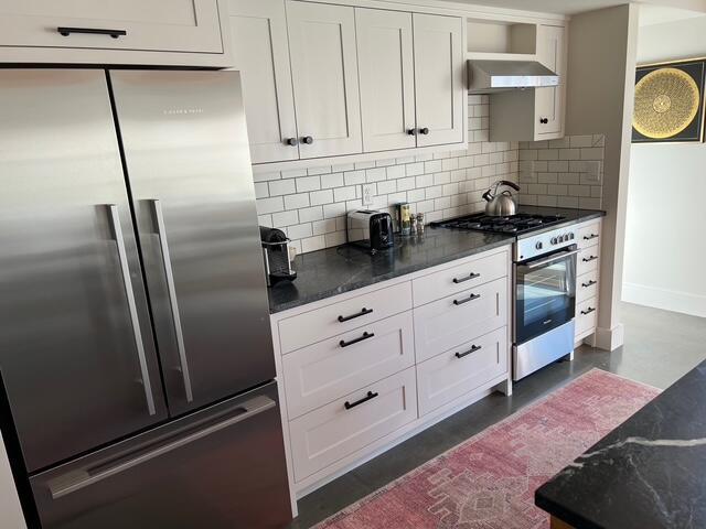 2 Seaview Rd, Orleans, MA 02653 - kitchen featuring wall chimney exhaust hood, decorative backsplash, white cabinets, baseboards, and appliances with stainless steel finishes