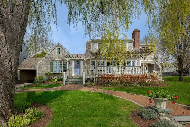 view of front of property with a pergola, a deck, a chimney, and a front lawn