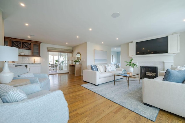 living area with light wood-style floors, a fireplace, and recessed lighting