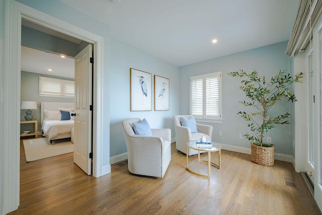 sitting room with baseboards, recessed lighting, wood finished floors, and visible vents