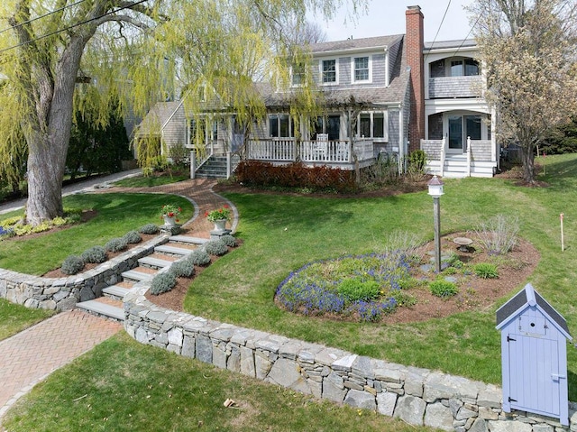 exterior space featuring a porch, roof with shingles, a chimney, and a front yard