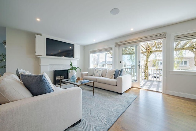 living room featuring a brick fireplace, recessed lighting, baseboards, and light wood-style flooring