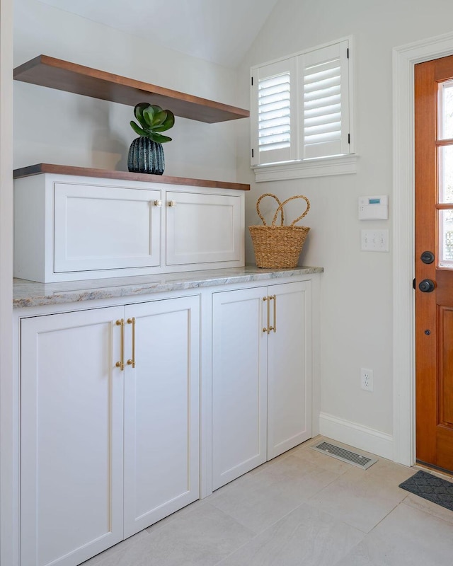 interior space featuring visible vents, baseboards, and vaulted ceiling