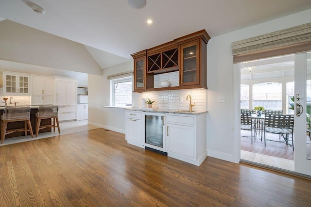 bar featuring baseboards, decorative backsplash, wine cooler, and wood finished floors