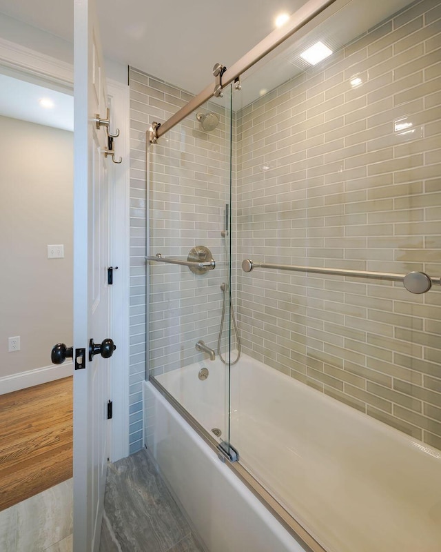 bathroom with shower / bath combination with glass door and baseboards