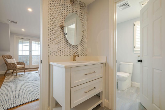 bathroom featuring toilet, baseboards, visible vents, and vanity
