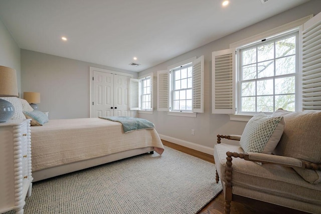 bedroom with recessed lighting, baseboards, wood finished floors, visible vents, and a closet