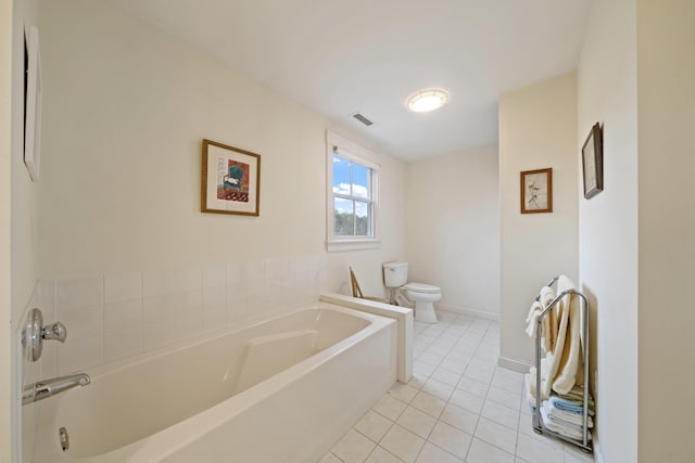 bathroom featuring a washtub, tile patterned floors, and toilet