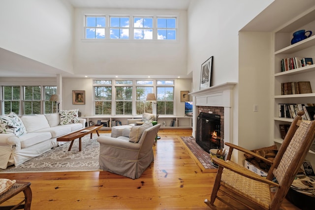 living room with plenty of natural light, light hardwood / wood-style floors, and a brick fireplace