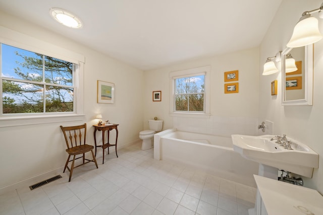 bathroom featuring tile patterned flooring, a tub, sink, and toilet