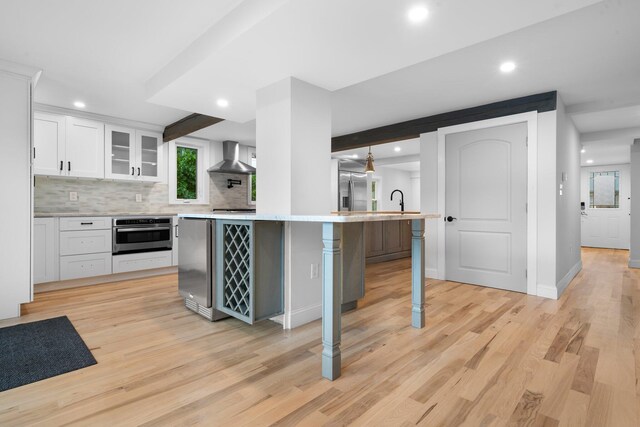 38 Mill St, Dennis Port, MA 02639 - kitchen with white cabinets, stainless steel appliances, a kitchen breakfast bar, wall chimney range hood, and light countertops