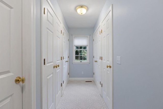 corridor featuring light tile patterned floors and baseboards