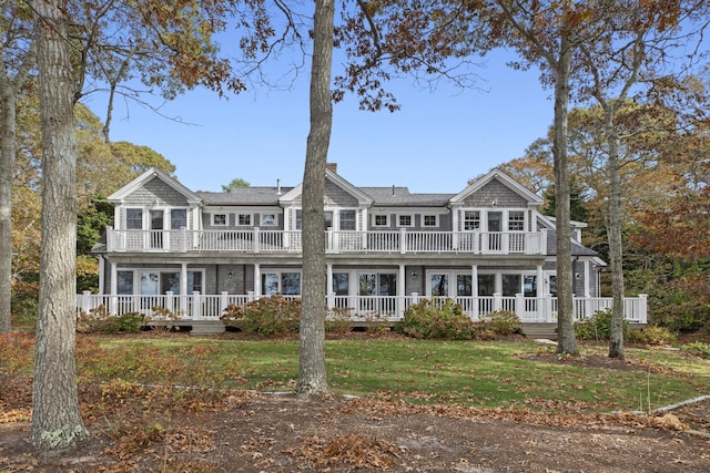 back of house featuring covered porch, a yard, and a balcony