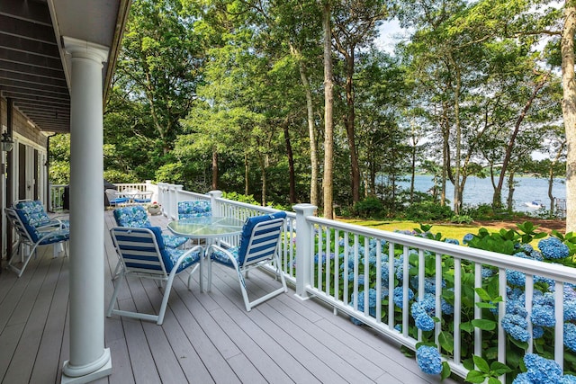 wooden terrace featuring a water view and outdoor dining space