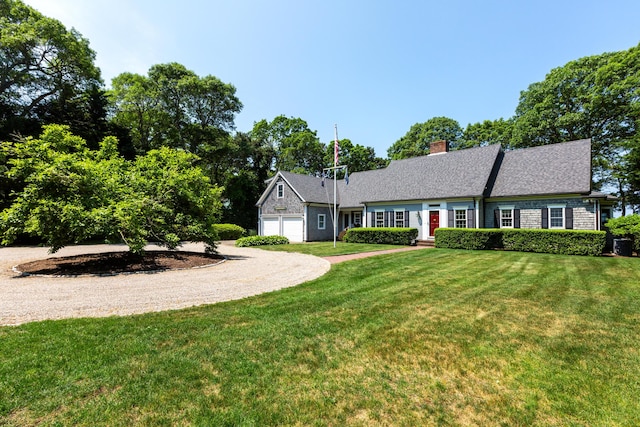 view of front facade with driveway, a chimney, and a front lawn