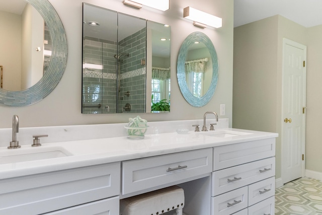 full bathroom featuring double vanity, a stall shower, a sink, and baseboards