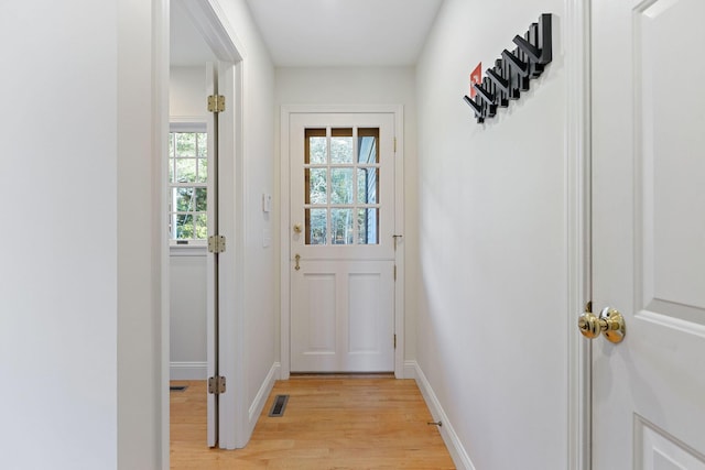 doorway featuring light wood-type flooring, visible vents, and baseboards