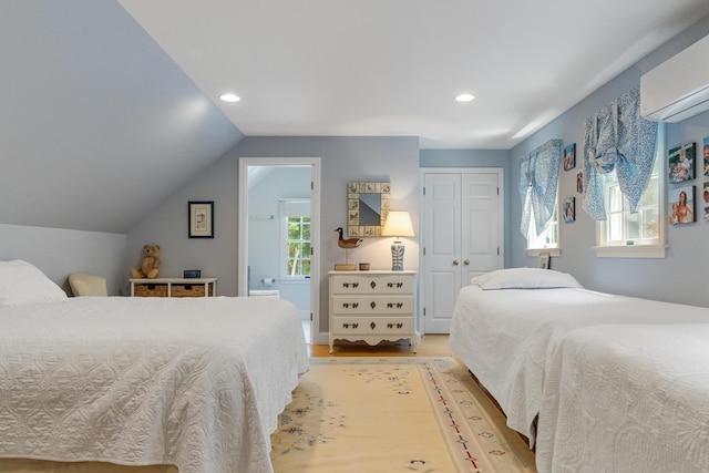 bedroom featuring a wall mounted air conditioner, vaulted ceiling, a closet, and light hardwood / wood-style flooring