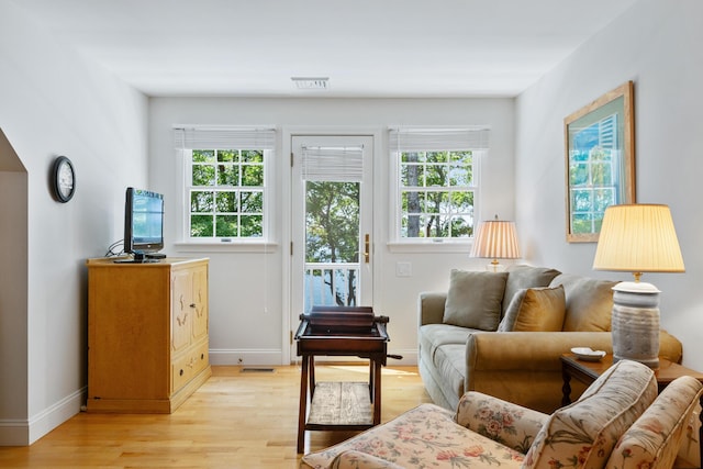 interior space with light wood-style floors, a healthy amount of sunlight, visible vents, and baseboards