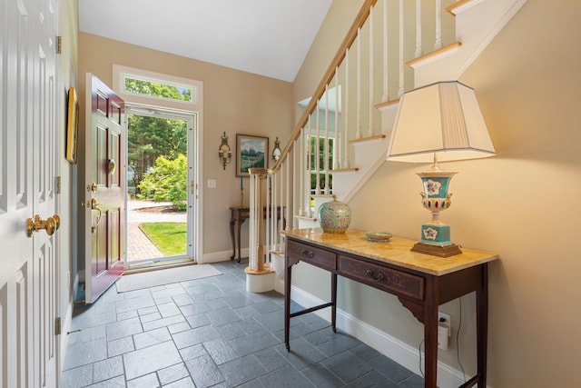 entryway featuring baseboards, stairway, and stone tile floors