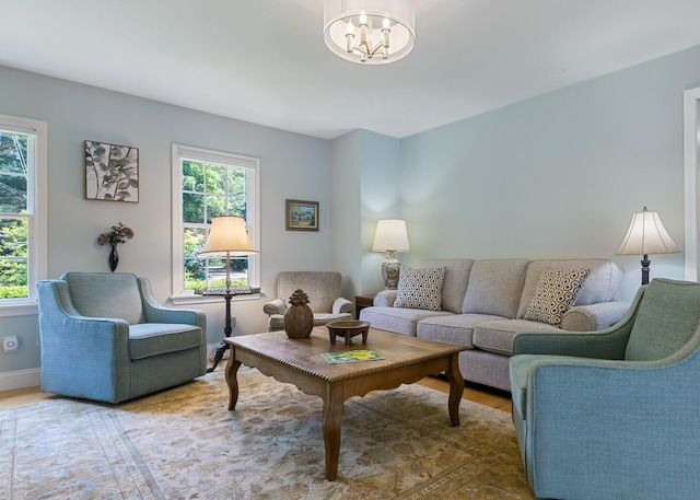 living room featuring an inviting chandelier, baseboards, a wealth of natural light, and wood finished floors