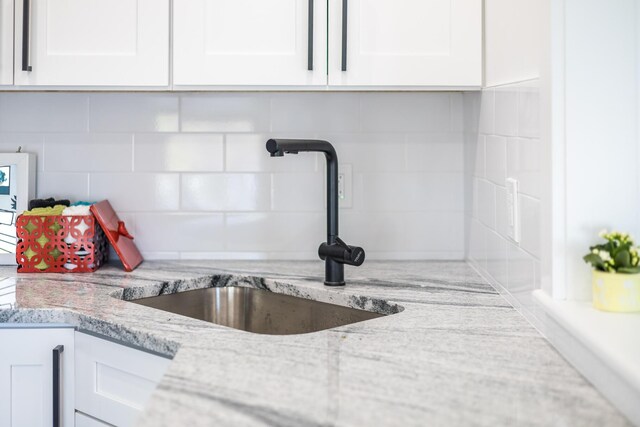 36 Pearl St Unit 2, Provincetown, MA 02657 - kitchen view of a sink, white cabinets, decorative backsplash, and light stone countertops