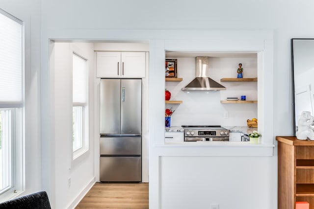 36 Pearl St Unit 2, Provincetown, MA 02657 - kitchen with appliances with stainless steel finishes, wall chimney exhaust hood, open shelves, light countertops, and white cabinets