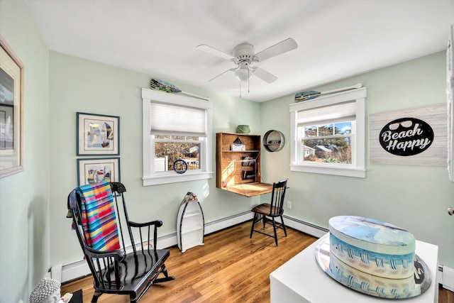 sitting room featuring hardwood / wood-style floors, ceiling fan, and a baseboard heating unit