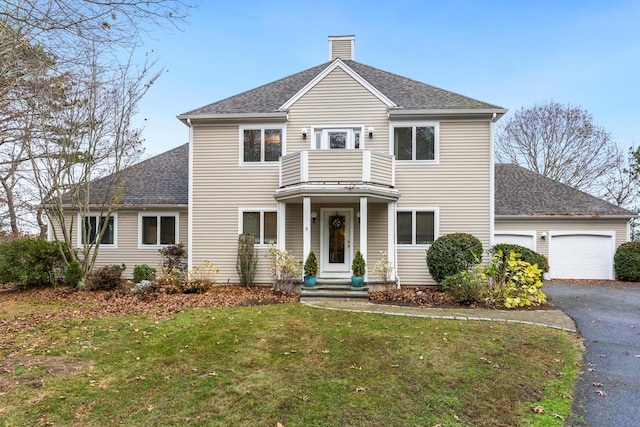 front of property with a garage, a front yard, and a balcony