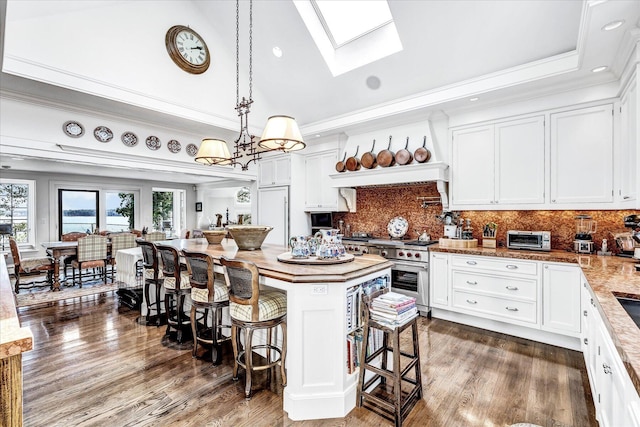 kitchen featuring a skylight, a breakfast bar, healthy amount of natural light, white cabinetry, and crown molding