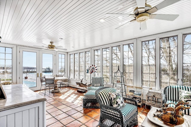 sunroom with plenty of natural light, french doors, and a water view