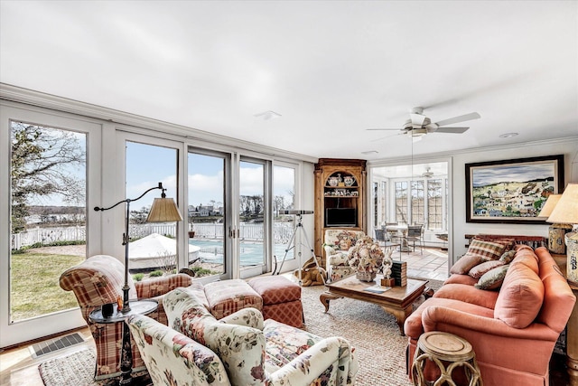 living area with crown molding and ceiling fan
