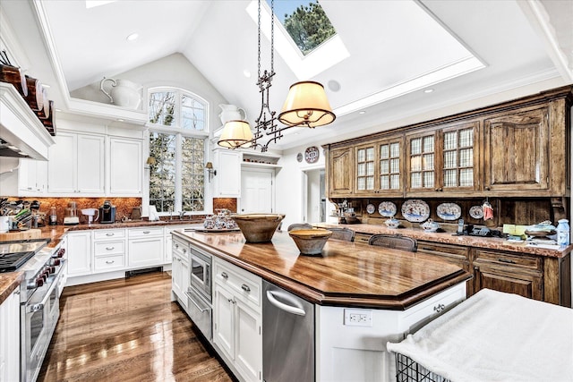 kitchen with appliances with stainless steel finishes, wooden counters, a kitchen island, a skylight, and white cabinets