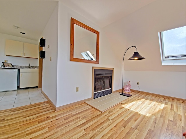 30 Norris Path, Teaticket, MA 02536 - unfurnished living room with a fireplace, light wood finished floors, vaulted ceiling, baseboards, and a skylight
