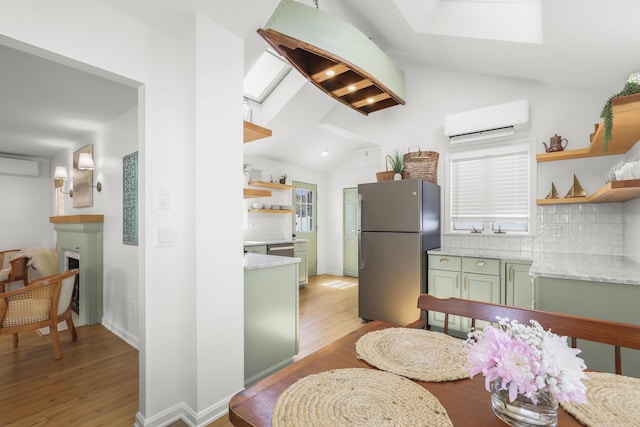 kitchen with open shelves, freestanding refrigerator, lofted ceiling, an AC wall unit, and green cabinetry