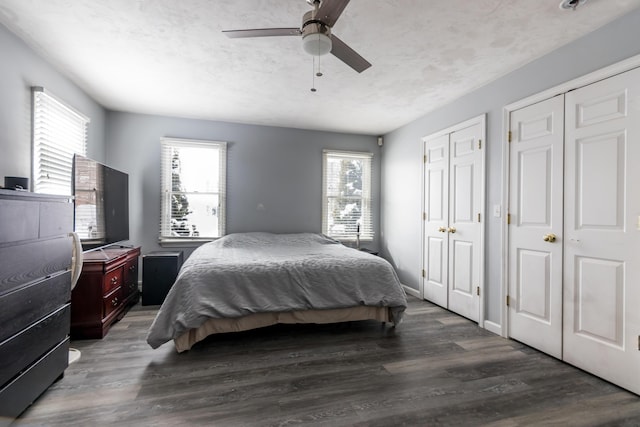 bedroom with multiple closets, ceiling fan, dark hardwood / wood-style floors, and a textured ceiling