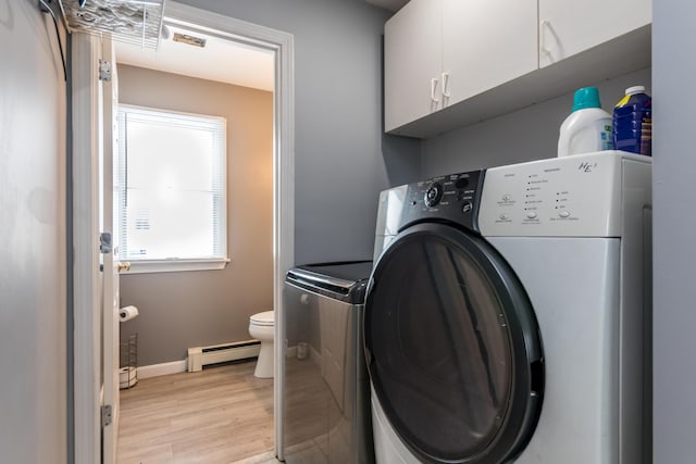 laundry room featuring a baseboard radiator, washing machine and dryer, cabinets, and light wood-type flooring