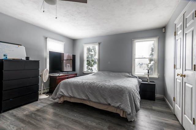 bedroom featuring dark wood-type flooring, ceiling fan, a textured ceiling, and a baseboard heating unit