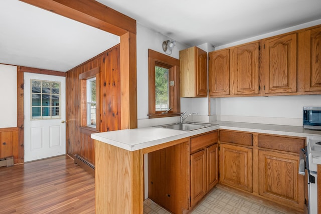 kitchen with white electric range, brown cabinetry, stainless steel microwave, light countertops, and a sink