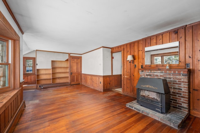 unfurnished living room with baseboard heating, wooden walls, hardwood / wood-style floors, lofted ceiling, and a baseboard radiator