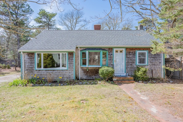 view of front facade with fence, a shingled roof, a chimney, and a front lawn