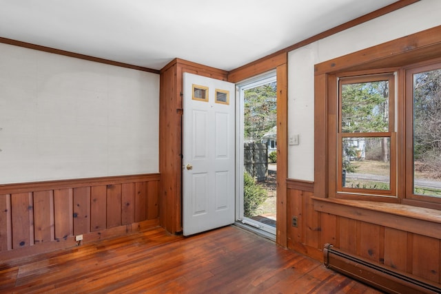 entrance foyer with a baseboard heating unit, wooden walls, a wealth of natural light, and hardwood / wood-style flooring