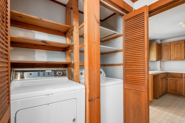 laundry room featuring laundry area, light floors, a sink, and washer and clothes dryer