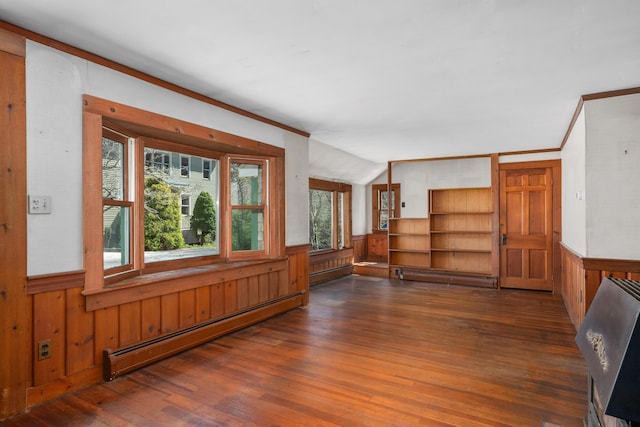 unfurnished room with wood walls, a baseboard heating unit, hardwood / wood-style floors, and a wainscoted wall