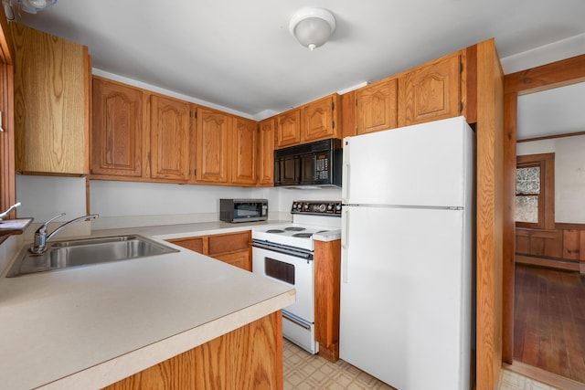 kitchen with white appliances, light floors, light countertops, a sink, and a baseboard radiator