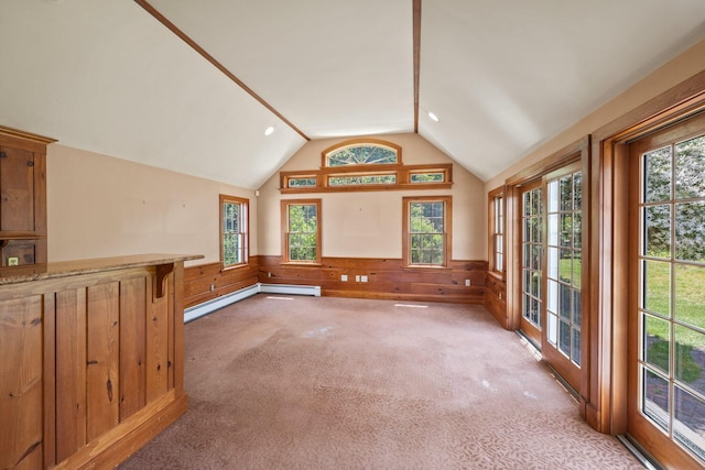 unfurnished living room featuring wood walls, light colored carpet, vaulted ceiling, and baseboard heating