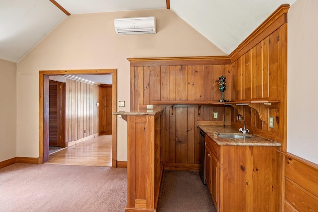 kitchen featuring kitchen peninsula, light carpet, stainless steel dishwasher, sink, and a wall mounted air conditioner