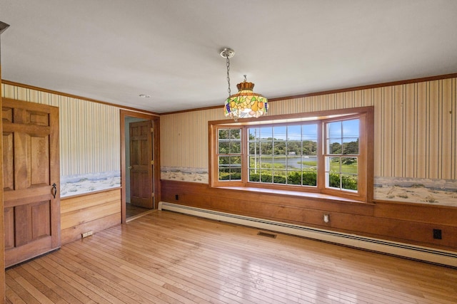 unfurnished dining area with hardwood / wood-style flooring, a baseboard heating unit, and crown molding